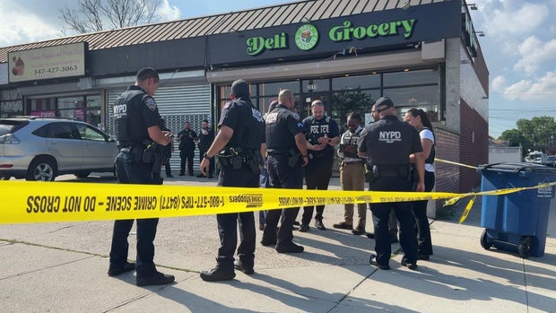 NYPD officers outside a Bronx deli blocked off by crime scene tape 
