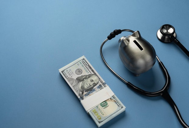 piggy bank with us dollar bills and stethoscope 