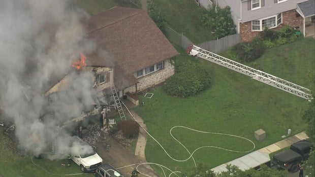 Overhead photo of house fire in Cherry Hill, heavy smoke and flames are seen, as well as a firetruck ladder pointed toward the home 