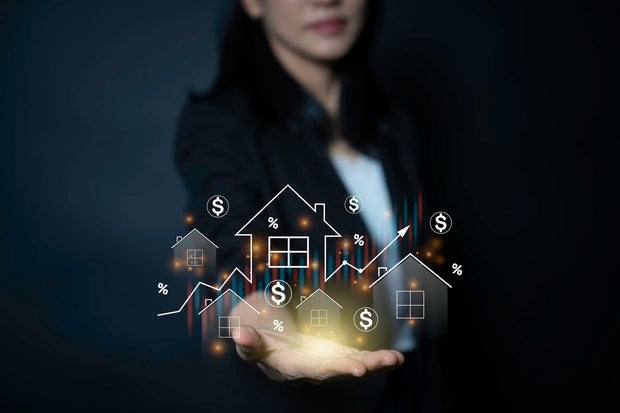 businesswoman holding virtual real estate icons and financial graphs over her hand to illustrate housing market trends and investment growth 
