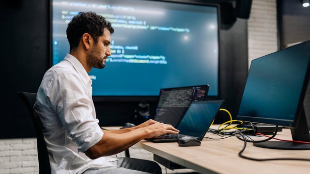 Professional software developer working late at night writing codes in an office. 