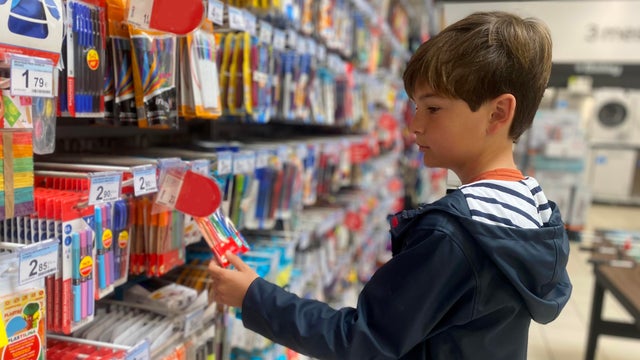 Boy looking for back to school stationery in a store 