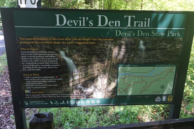 This photo of May 2020 shows a sign for a hiking trail at Dev's Den State Park in West Fork, Ark. 