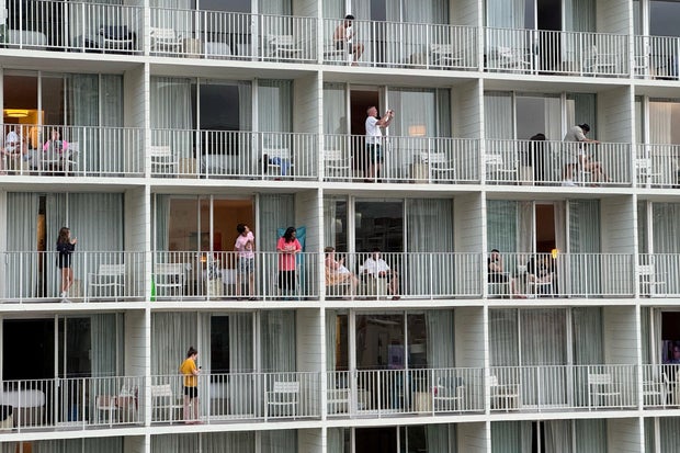 Vacationers stand on balconies at the 'Alohilani Resort looking towards Waikiki Beach after authorities warned of the possibility of tsunami waves 