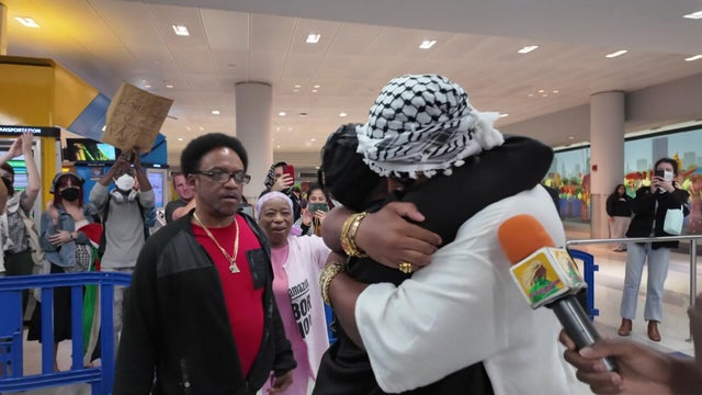 Chris Smalls hugs his mom at JFK Airport while supporters watch 