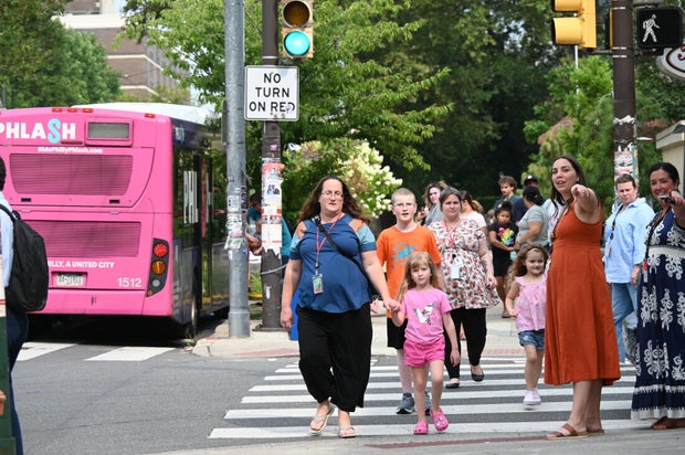 Adults and kids walk in the street toward the event