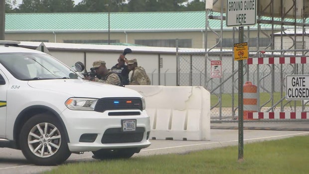 Military police are positioned outside a gate to Fort Stewart in Georgia following an active shooter incident Aug. 6, 2025. 