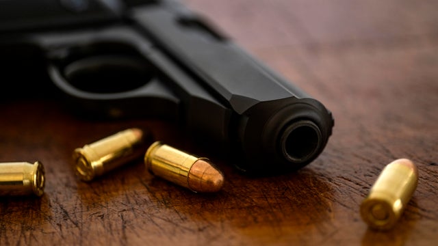 Gold bullets and pistol on wooden surface 