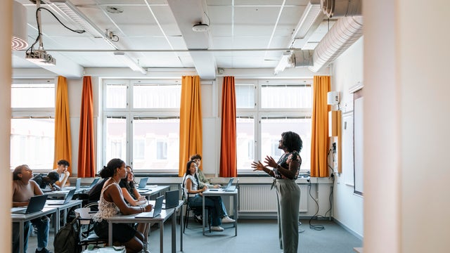 Teacher explaining students in classroom at high school 