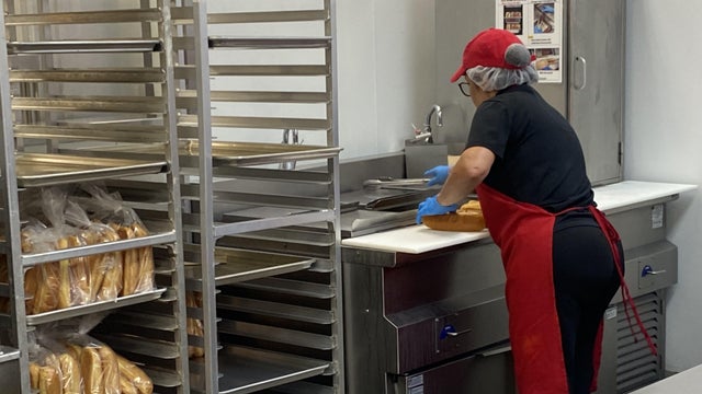 Costco, cafeteria, worker, employee, uniform, apron, food preparation, hot dog, food court, restaurant, Florida, megastore, hot dog bun, bun, food, fast food, discount, woman, one person 