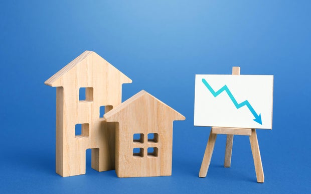 Figurines of houses and down arrow chart negative trend easel. Big promotions and discounts on home sales. Special purchase offers. Low demand for real estate and housing, economic downturn recession. 
