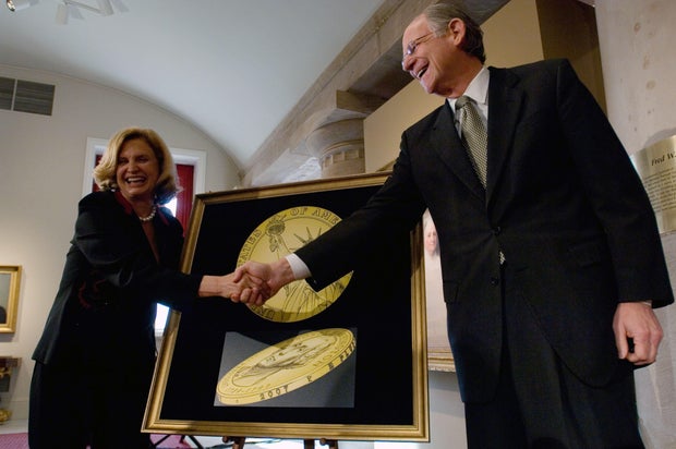 Rep. Michael Castle of Delaware shakes hands with Rep. Carolyn Maloney of New York in front of a drawing representing the "tails" or obverse side of the new presidential $1 coin, during an unveiling ceremony at the National Portrait Gallery on Nov. 20, 2006, in Washington, D.C.