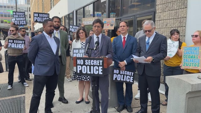 Lawmakers gather for a press conference, a sign on the podium says No Secret Police 