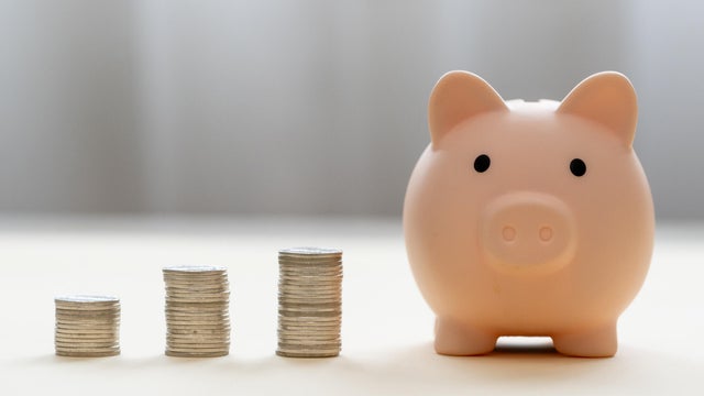 Piggy bank and stack of coins money on wooden background. Save money for prepare in future and pension retirement. Earning interest on savings. Growing your wealth and saving money concept 