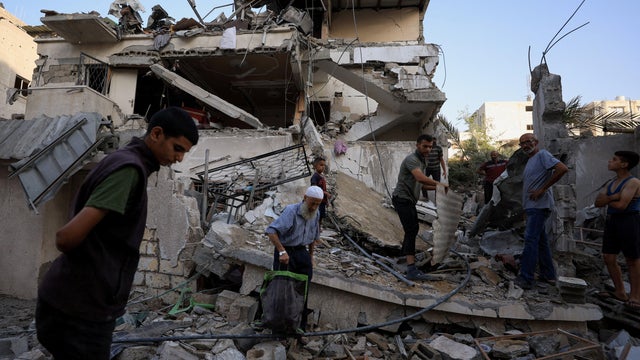 Palestinians inspect the site of an overnight Israeli strike on a house, in Gaza City 