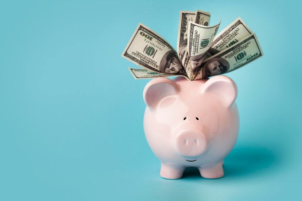 Pink piggybank stuffed with dollar bills 