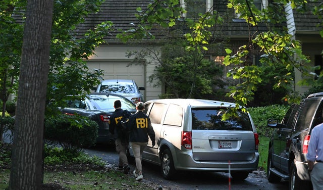 FBI agents walk outside the home of John Bolton 