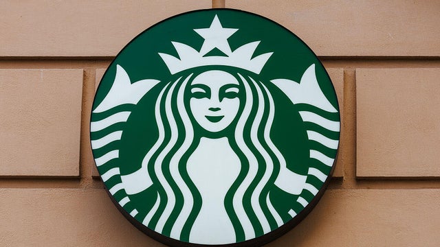 A Starbucks logo is seen on a beige wall 