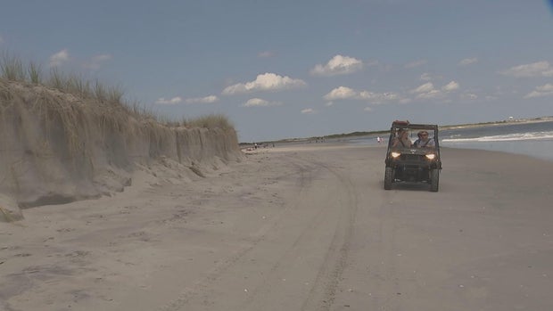 A small cliff is seen on the beach in Strathmere as a Beach Patrol four by four drives by 
