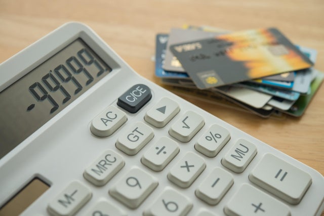 White calculator shows minus delinquent and many credit cards on wooden table background. 