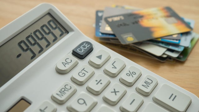 White calculator shows minus delinquent and many credit cards on wooden table background. 