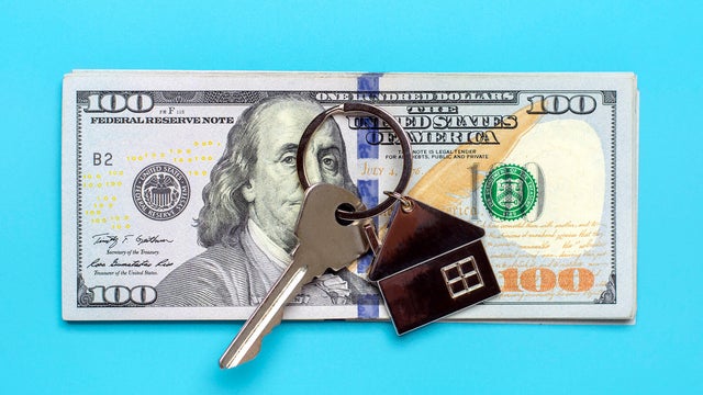 house or apartment key, dollars banknote isolated on blue background 