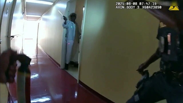Body cam video shows a woman standing in the doorway of an apartment and pointing a large knife at officers 