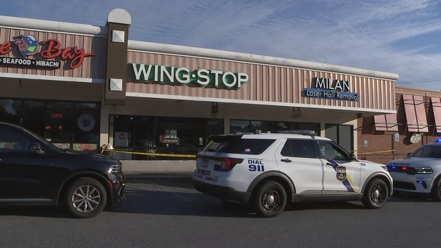 A Philadelphia police car and yellow police tape are seen outside a Wingstop store 