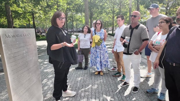 Christina Stanton stands at the 9/11 Memorial Glade and speaks to a tour group. 