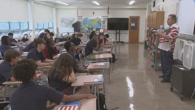 A teacher speaks to his class at Cardinal O'Hara on Sept. 11, he's wearing a shirt with an American flag and an eagle on it 