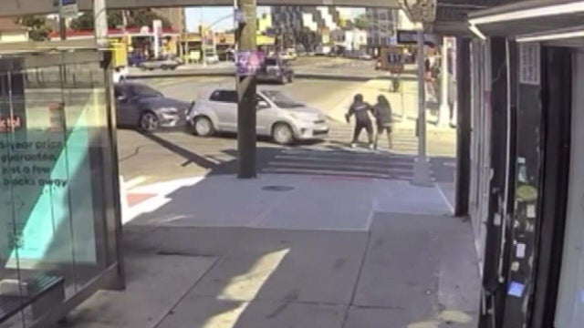 Surveillance video shows two pedestrians in a crosswalk in front of two vehicles colliding 