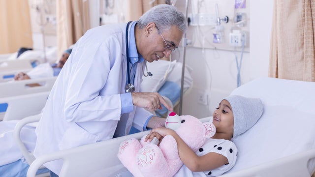 Doctor having fun with little girl patient at hospital.