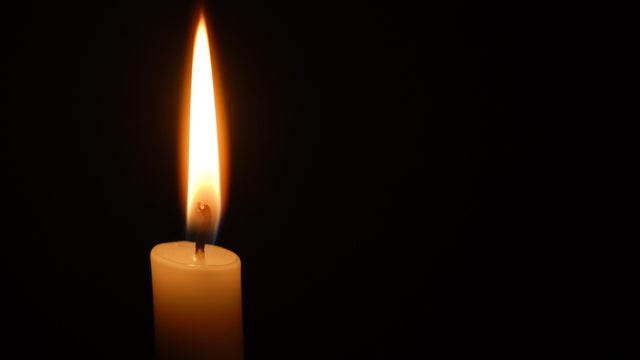Single candle flame on horizontal black background 