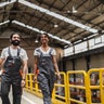 Happy workers walking through warehouse while smiling at each other 