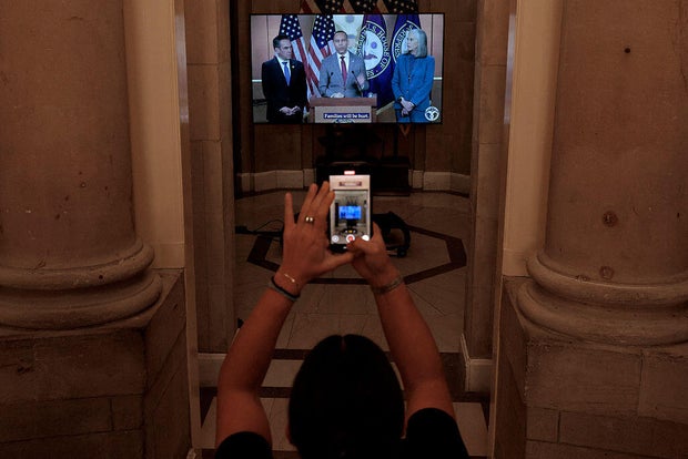 House Speaker Mike Johnson of Louisiana places a television in the doorway of his Capitol office in Washington, D.C., on Sept. 30, 2025, showing video of Democrats discussing a government shutdown. 