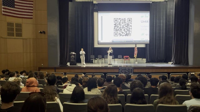 A speaker talking to students in a school auditorium 