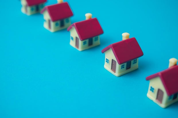 Row of small houses on blue background copy space. 
