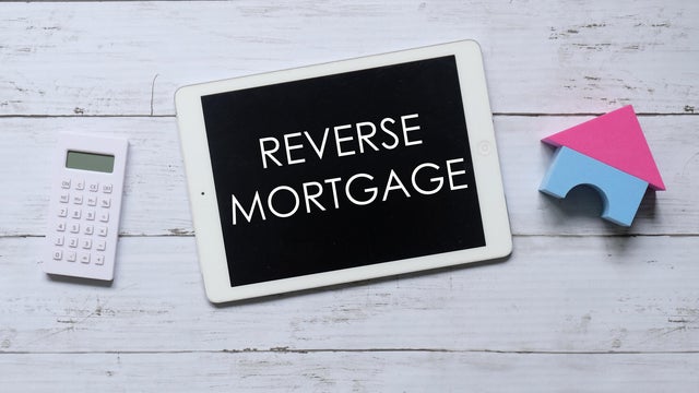 Top view of calculator,house model and tablet written with REVERSE MORTGAGE. Business and finance concept. 