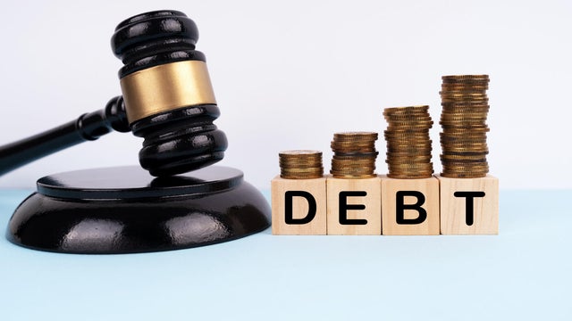 Gavel, coins stacks and wood blocks with DEBT written on them. Finance and law concept 