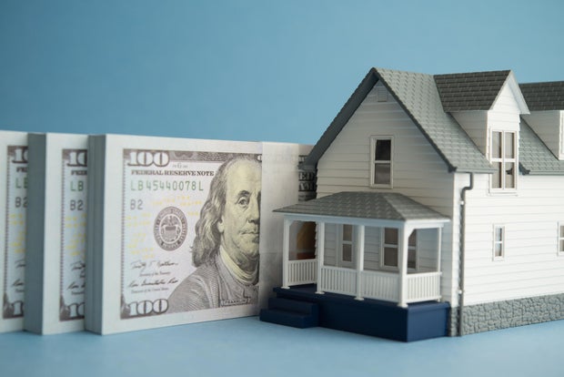 House and US dollar banknotes on blue background. 