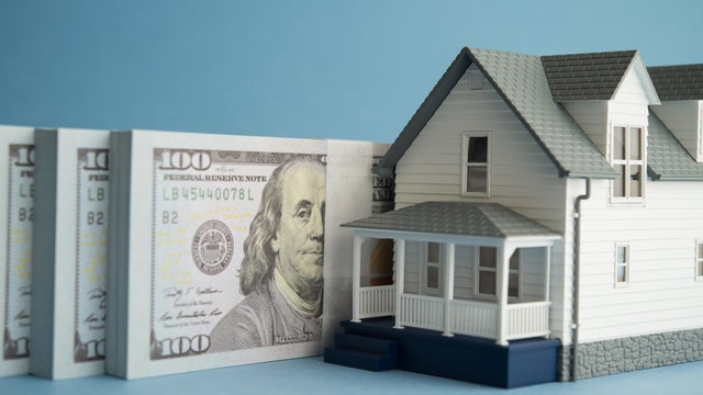 House and US dollar banknotes on blue background. 