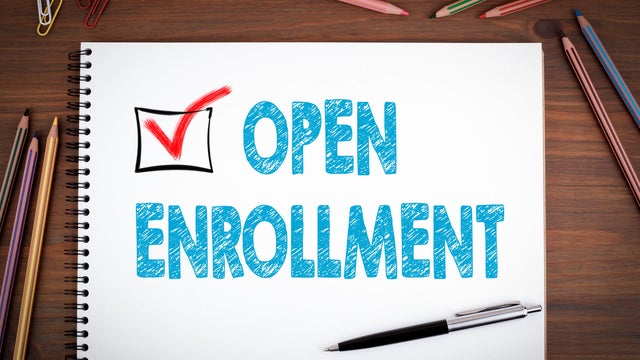 Open Enrollment. Notebooks, pen and colored pencils on a wooden table 