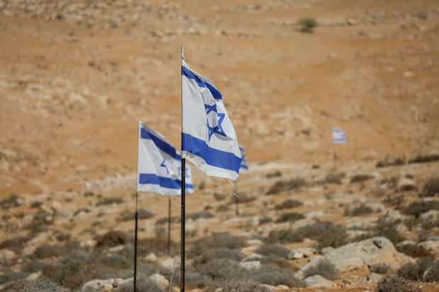 Israeli flags fly above olive trees in the village of Hawara, in the Masafer Yatta area, south of Hebron, West Bank, on Oct. 7, 2025. 