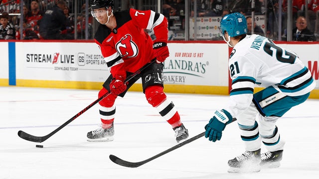 Dougie Hamilton #7 of the New Jersey Devils controls the puck as Alexander Wennberg #21 of the San Jose Sharks defends during the second period at Prudential Center on October 24, 2025 in Newark, New Jersey.