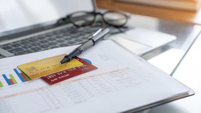 View of desk with credit card in the wallet on computer laptop. 