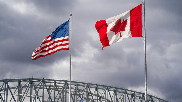 The U.S. and Canadian flags flutter next to the Blue Water Bridge border crossing in Point Edward, Ontario, on Oct. 24, 2025.