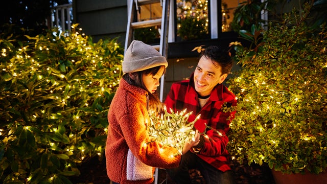 Medium shot girl holding lights while decorating home for Christmas 