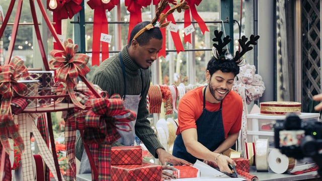Retail clerks wrapping gift in Christmas decoration store 