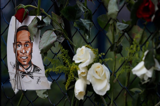 An image of Ahmaud Arbery hangs alongside roses in a memorial display 