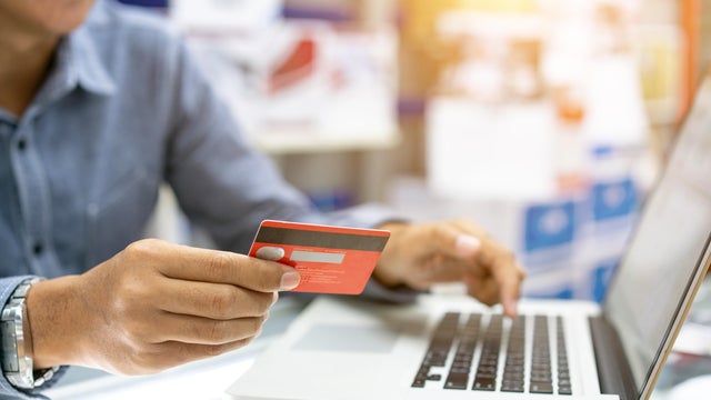 Hands holding credit card, typing on the keyboard of laptop, onine shopping detail close up 